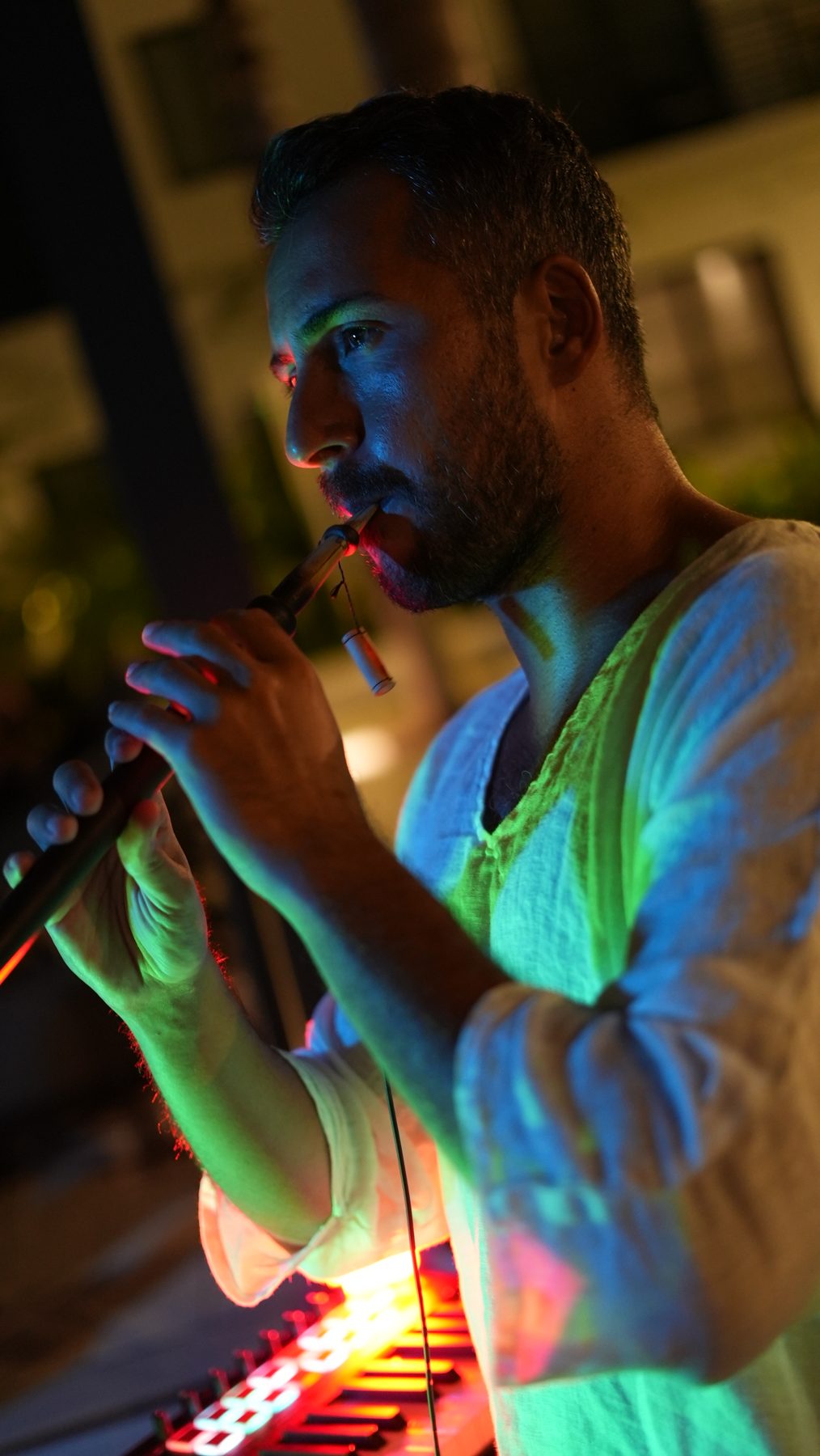 Alp Akmaz playing the Balaban beside a neon sign